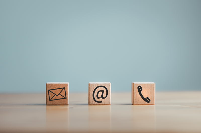 three wooden blocks sit on a table with a mail, email, and phone icon